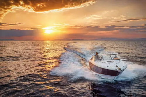 speedboat crossing water at sunset